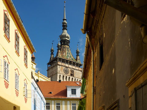 The clock tower from Sighisoara as seen from a street with colorful houses from the medieval fortress