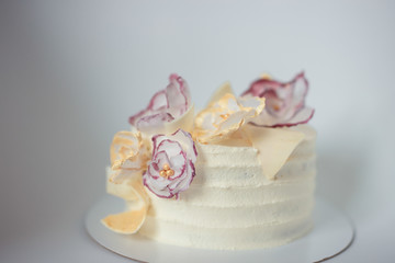 white cake on a white background with a wafer flowers
