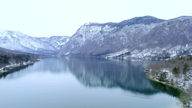 Aerial flying over the Bohinj lake near mountains in winter