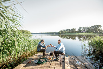 Vue paysage sur le lac avec deux amis masculins assis avec de la bière pendant le processus de pêche