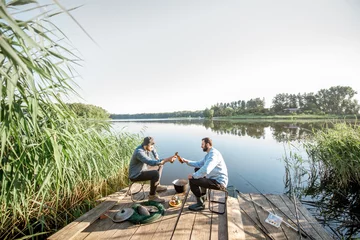 Papier Peint photo Lavable Pêcher Vue paysage sur le lac avec deux amis masculins assis avec de la bière pendant le processus de pêche