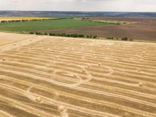 Naklejka premium aerial top view to harvested field with straw bales in summer