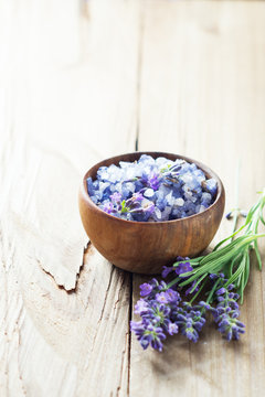 Lavender salt with flowers on wooden table.