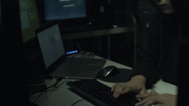 Hacker connecting with his computers in a dark basement