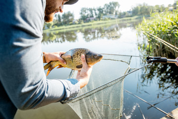 Fisherman getting caught fish from the fishing net near the lake in the morning