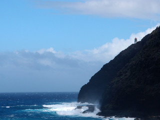 Makapu'u Lighthouse on cliffside as wave crashing into rocks below