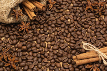 Background of coffee beans. Coffee texture. Cinnamon sticks and cardamom.