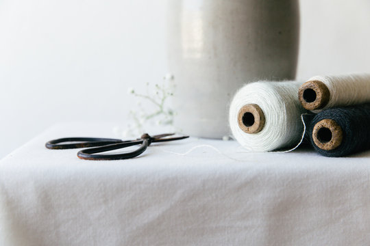 Bobbins of string and scissors on a white table top.