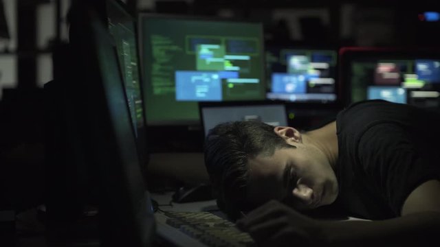 Computer developer and hacker sleeping on his desk at night