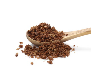 Crunchy chocolate granola, muesli pile in wooden spoon isolated on white background