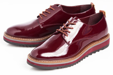 Deep red shiny pair of shoes on a white background.