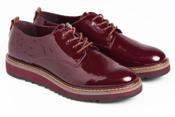 Deep red shiny pair of shoes on a white background.