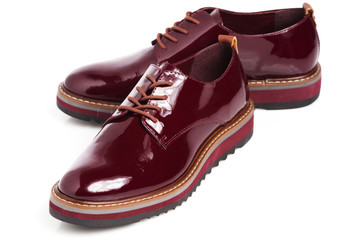 Deep red shiny pair of shoes on a white background.