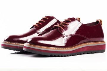 Deep red shiny pair of shoes on a white background.