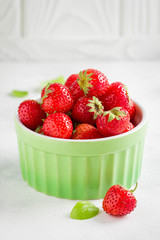 Small strawberry in green cup, fresh juicy summer berry on light background, home garden