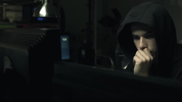 Hacker connecting with his computers in a dark basement