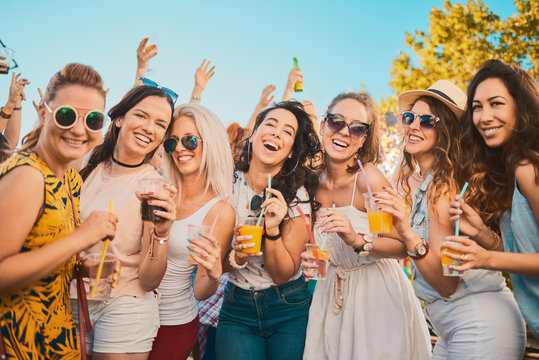 Group of female friends posing and having a good time at the outdoor party/music festival 