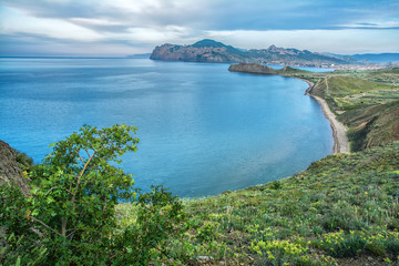 Fototapeta na wymiar Beautiful blue sea, greenery on the shore and mountains in the background