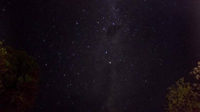 A rotating astrophotography time-lapse of the milk-way galaxy by the glow of a camp fire.
