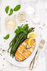 grilled perch with green beans and lemon on white dish