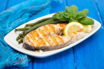 grilled perch with green beans and lemon on white dish