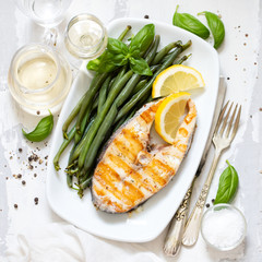 grilled perch with green beans and lemon on white dish