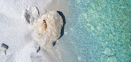 Luftaufnahme einer Frau, die auf einem Felsen sonnt in Lalaria Beach, Skiathos. 