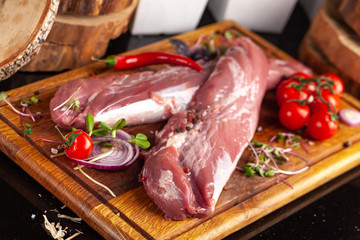 Raw beef, veal fillet, fillet, on a wooden board with cherry tomatoes, chilli pepper, micro greens....
