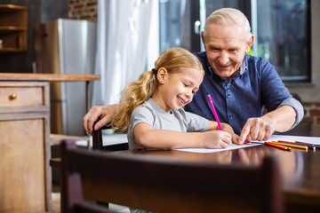 Nice little girl drawing with her grandfather