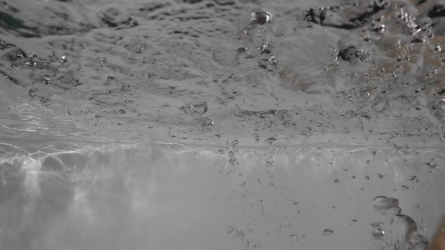 A hand hits the water surface in a swimming pool
