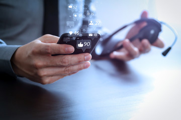 businessman using VOIP headset with mobile phone and concept communication call center on wooden desk