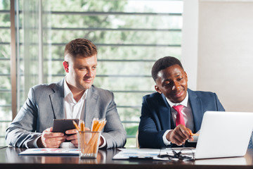Portrait of two business partners sitting at a table together and working.