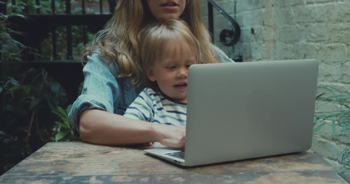 Mother trying to use laptop with toddler interrupting