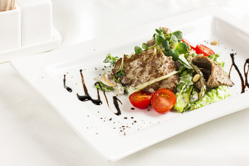 Warm salad with meat, mushrooms, cherry tomatoes, pine nuts and herbs