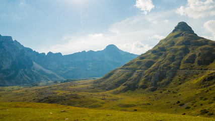 Obraz premium Gorgeous panoramic view of mountains in cloudy day with few peaks and road, autumn Montenegro, Durmitor national park