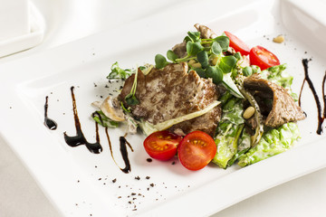 Warm salad with meat, mushrooms, cherry tomatoes, pine nuts and herbs