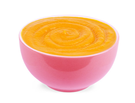 Pumpkin and carrot baby puree in round dish isolated on white background