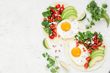 Healthy flatbread with avocado, egg and mexican salsa on concrete background. Top view, copy space...