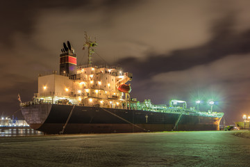 Massive moored oil tanker at night with a dramatic cloudy sky, Port of Antwerp, Belgium.