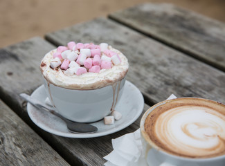 A luxury hot chocolate drink in a posh cup and saucer with whipped cream and marshmallows melting...