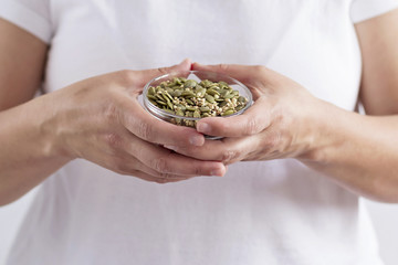 A person holding a bowl with seeds