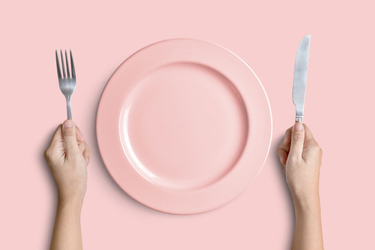 Pink plate with silver fork and knife on pink background with clipping path