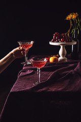 cropped shot of woman taking glass of wine from table with fruits on black