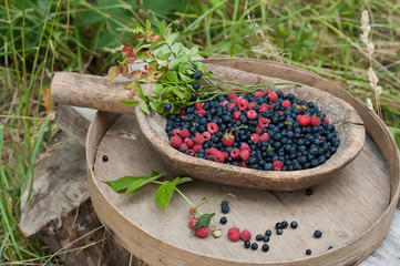 Forest berries of blueberries and raspberries on rough wooden utensils. Retro vintage style. summer on a farm, in a village.
