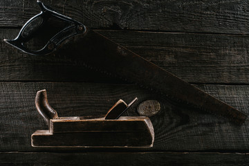  top view of retro rusty saw and woodworker plane on wooden surface