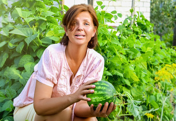 Portret of happy woman with watermelon growing in the garden