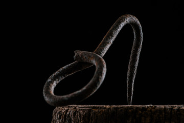  close up view of vintage hook on wooden stump isolated on black