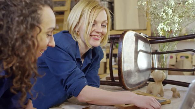 Two beautiful Caucasian women smiling and talking to listeners when running webinar in carpentry workshop