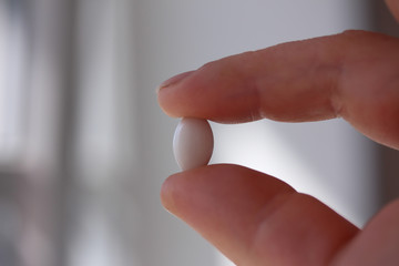 Male hand holding pill.

