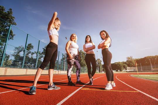 Group Of Female Runners Standing The Race. Four Women At Athletics Stadium